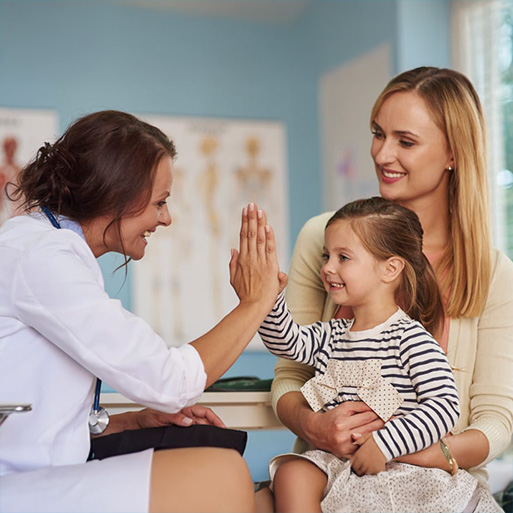 Image of a pediatrician high-fiving a young patient in the exam room
