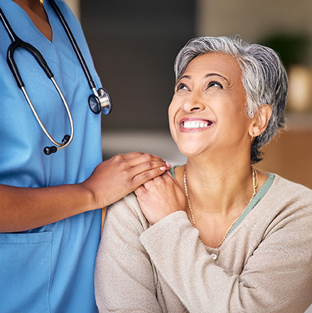 seated smiling woman her doctor's hand on her shoulder